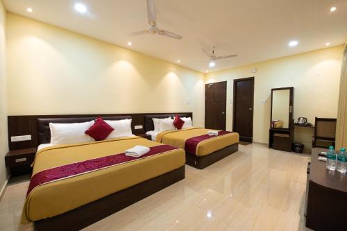 a hotel room with two beds and a table at Sugam Resort & Convention Centre in Chennai