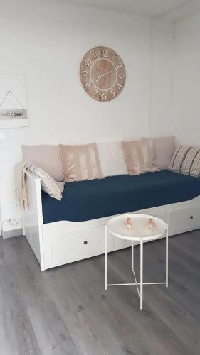 un canapé blanc avec une horloge et une table dans l'établissement Superbe studio 5 min de la plage, à La Grande Motte