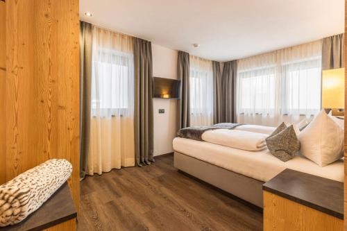 a bedroom with a large bed and windows at Chalet Miriam in Selva di Val Gardena