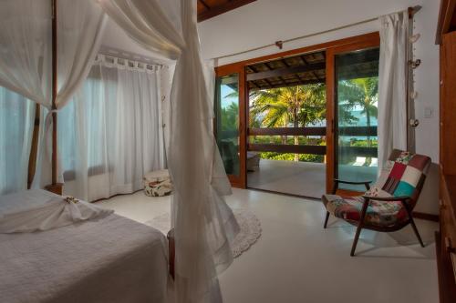 Un dormitorio con una cama y una silla y una ventana. en Casa Villa Cristian Villa Venezia Pe na Areia, en Arraial d'Ajuda