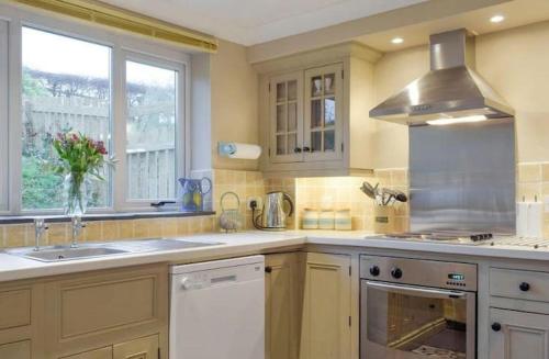 een keuken met een wastafel en een fornuis top oven bij Broadhaven Cottage, Freshwater East, Pembs in Pembroke