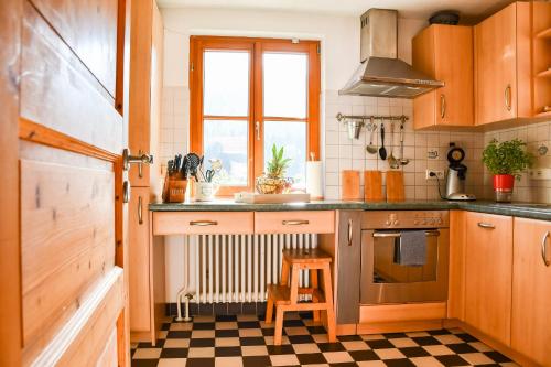 a kitchen with wooden cabinets and a checkered floor at Ferienhaus Müllerswald in Schenkenzell