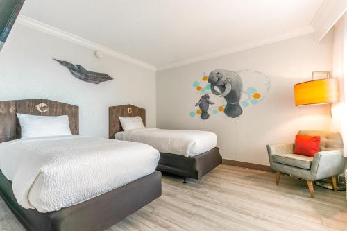 a hotel room with two beds and a chair at Winter the Dolphin's Beach Club, an Ascend Collection Hotel in Clearwater Beach
