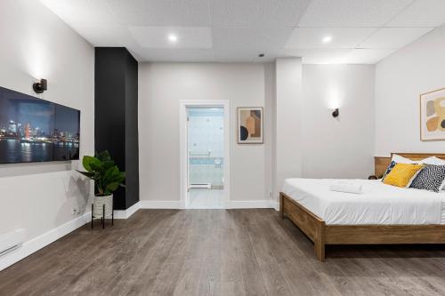 a bedroom with a bed and a tv on a wall at Le Sand & Stone Hotel in Montréal