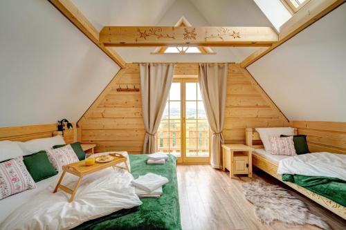 a attic room with two beds and a table at Jedlinowo Chata Domek Góralski in Szaflary