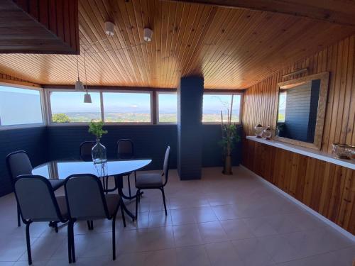 uma sala de jantar com mesa, cadeiras e janelas em BAIRRADA SUITE HOUSE BY HOTEL PARAISO em Oliveira do Bairro