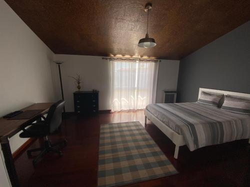 a bedroom with a bed and a desk and a window at BAIRRADA SUITE HOUSE BY HOTEL PARAISO in Oliveira do Bairro