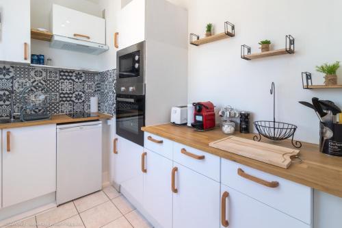une cuisine avec des armoires blanches et un comptoir en bois dans l'établissement ZenBNB - L'émeraude - Beautiful Studio Apartment - Near Tram Station for Geneva, à Annemasse