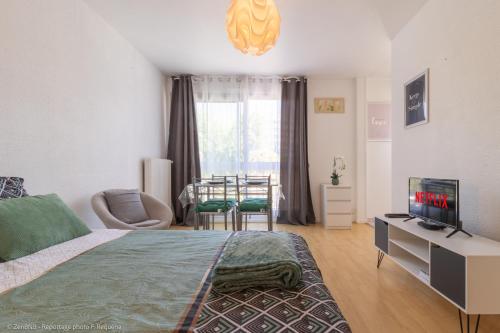 um quarto com uma cama, uma televisão e uma mesa em ZenBNB - L'émeraude - Beautiful Studio Apartment - Near Tram Station for Geneva em Annemasse