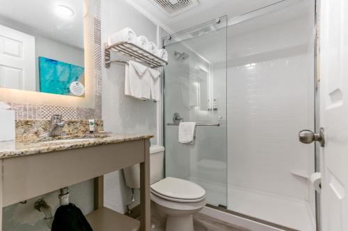 a bathroom with a toilet and a glass shower at Winter the Dolphin's Beach Club, an Ascend Collection Hotel in Clearwater Beach