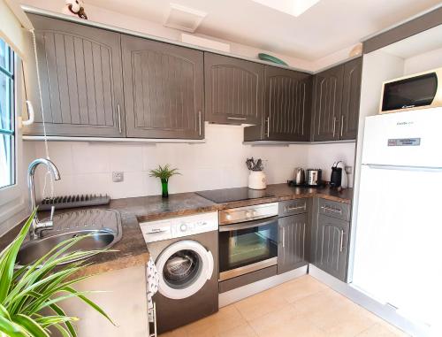 a kitchen with wooden cabinets and a washer and dryer at Deluxe Home from Home in Caleta de Fuste in Caleta De Fuste