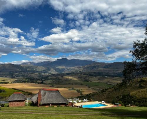 a resort with a pool and mountains in the background at Graceland Self-Catering Cottages in Winterton