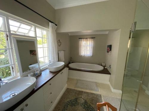 a bathroom with two sinks and a tub and a shower at Protea Manor in George