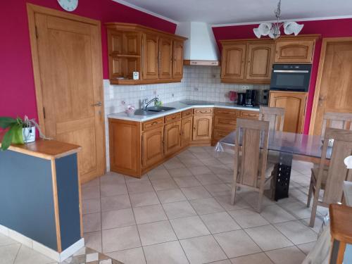 a kitchen with wooden cabinets and a table at Bonheur à la campagne in Bastogne