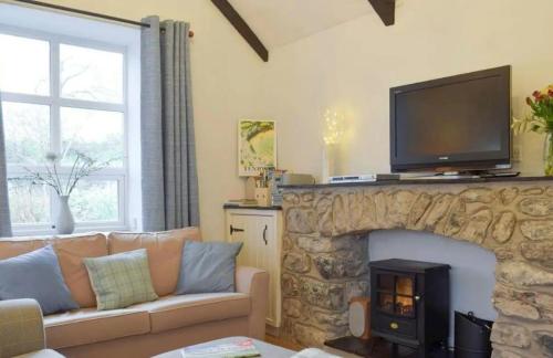 a living room with a stone fireplace with a television on top at Broadhaven Cottage, Freshwater East, Pembs in Pembroke
