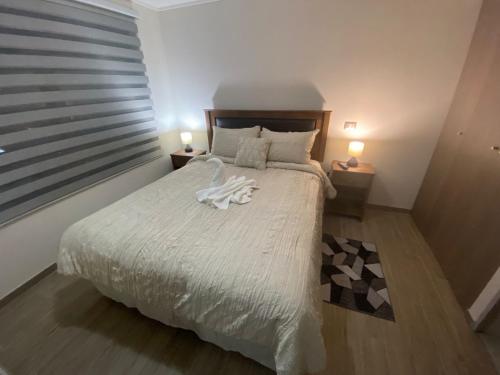 1 dormitorio con 1 cama blanca grande y 2 lámparas en Pleno Centro Apart en Antofagasta