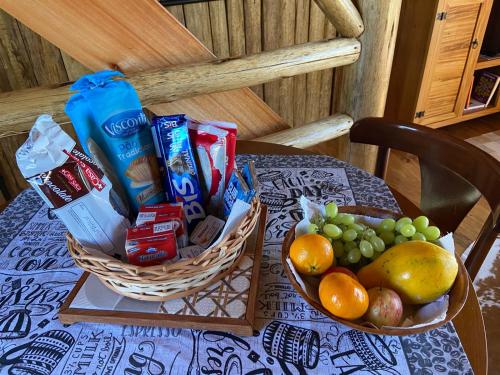 een tafel met een mand met eten en een fruitmand bij Pousada Parador 33 in Biguaçu