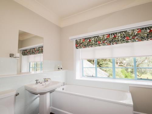 a white bathroom with a sink and a tub and a window at Inverewe - House Apartment in Achnasheen