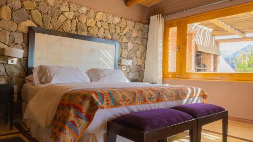 a bedroom with a large bed with a stone wall at Las Marías Hotel Boutique in Tilcara