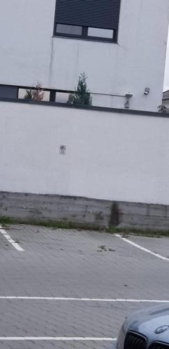 a parking lot with a white wall next to a street at Apartament Vila Brana Sibiu Selimbar str Nicolae Brana Nr 63 Ap 4 in Şelimbăr