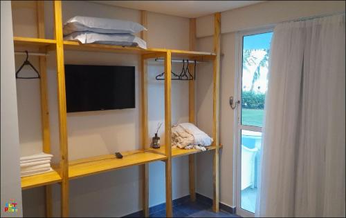 a room with shelves with a tv and a window at Best location of the development, ground floor seafront in Porto De Galinhas