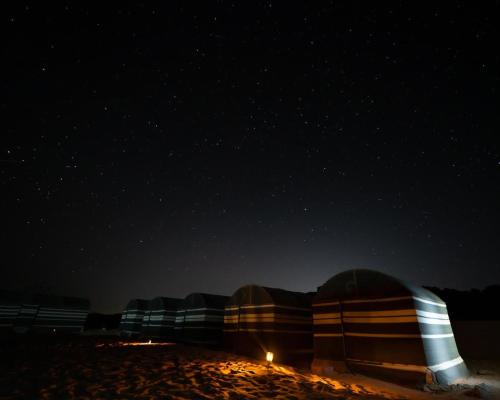 a group of tents on the beach at night at Desert Dream Camp in Wadi Rum