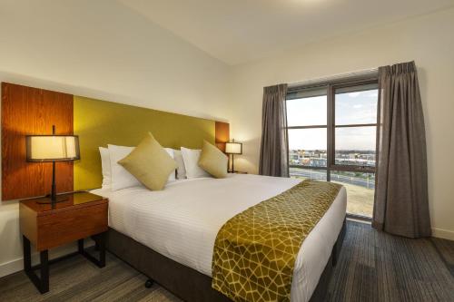 um quarto de hotel com uma cama grande e uma janela em Quest Melbourne Airport em Melbourne