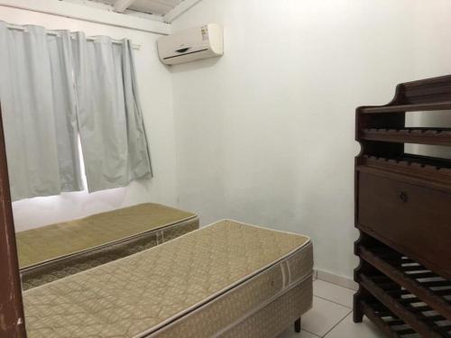 a bedroom with two beds and a window and a dresser at Pousada Residencial Família Dragone in Bombinhas