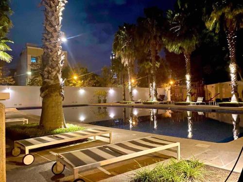 a swimming pool with palm trees in front of a building at Diseño Único Con 2 Recámaras, Alberca Y Gimnasio in Guadalajara