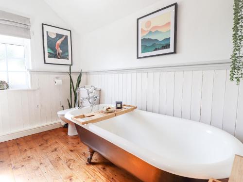 a large bath tub in a white room with a toilet at Rose Cottage in Louth