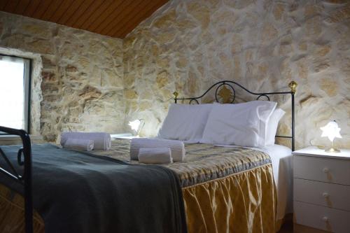 1 dormitorio con 1 cama con pared de piedra en Casa da Pedra, en Ansião