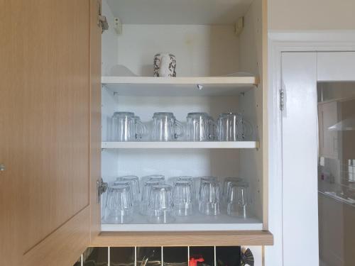 un armario lleno de frascos de cristal transparente en una cocina en London Luxury 2 Bedroom Apartment 5 min from tube station with free parking, en Wanstead