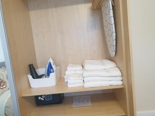 een stapel handdoeken op een plank in een badkamer bij London Luxury 2 Bedroom Apartment 5 min from tube station with free parking in Wanstead