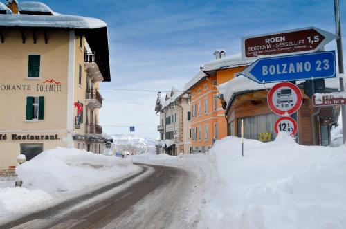 a street covered in snow next to buildings at Hotel Villa Argentina Ronzone in Ronzone