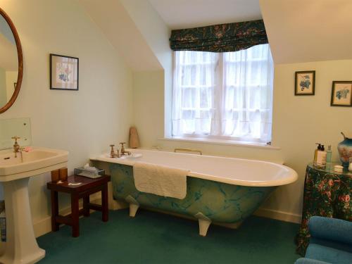 La salle de bains est pourvue d'une grande baignoire et d'un lavabo. dans l'établissement White Rose Cottage, à Robin Hood's Bay