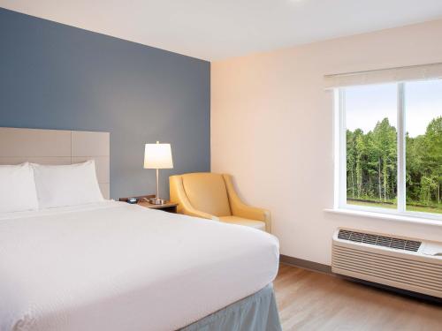 a bedroom with a bed and a chair and a window at Extended Stay America Suites - Charlotte - Matthews in Charlotte