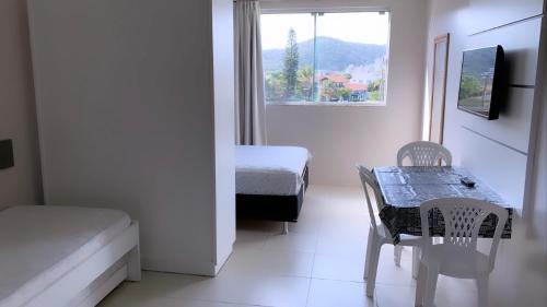 a bedroom with a table and a bed and a window at Residencial Florida in Bombinhas
