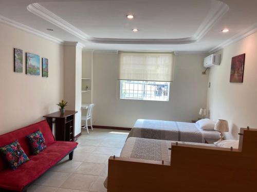 1 dormitorio con 1 cama y 1 sofá rojo en DORAL SUITE ¡CERCA DEL AEROPUERTO! en Guayaquil