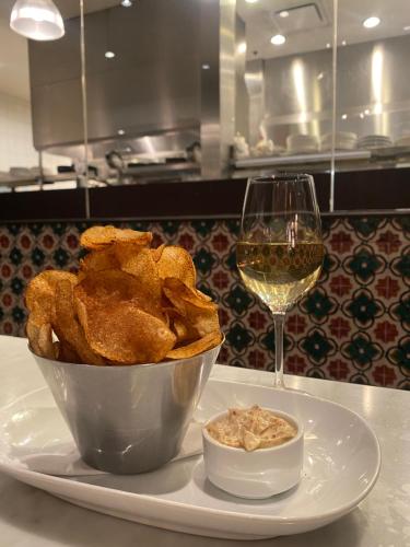 a plate with a bowl of chips and a glass of wine at Century Plaza Hotel in Vancouver