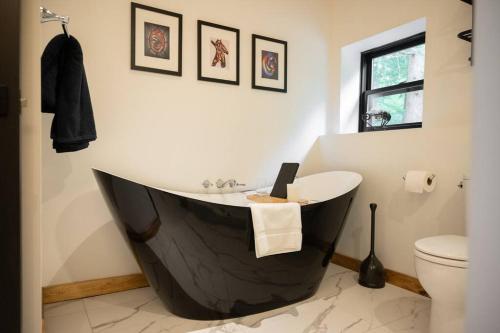 a bathroom with a black tub and a toilet at Private Off Grid Cottage Nestled in Nature With Waterfront in Barrys Bay