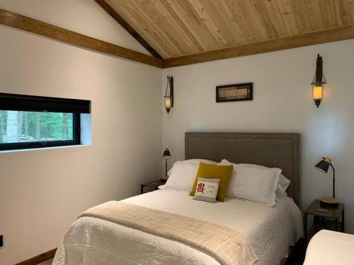 um quarto com uma cama com lençóis brancos e uma janela em Private Off Grid Cottage Nestled in Nature With Waterfront em Barrys Bay