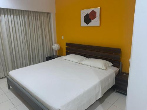 a bedroom with a large white bed and a yellow wall at JACO BAY in Jacó