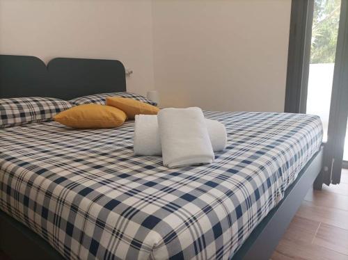 uma cama com um cobertor e almofadas de xadrez azul e branco em Eraclea Minoa Apartments em Eraclea Minoa