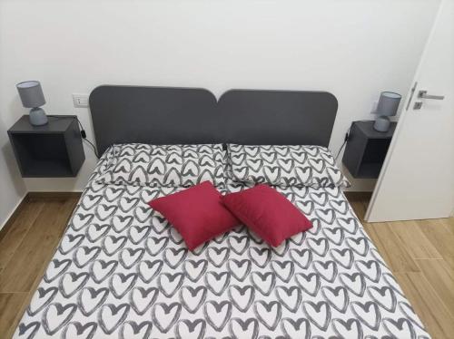 a large bed with two red pillows on it at Eraclea Minoa Apartments in Eraclea Minoa