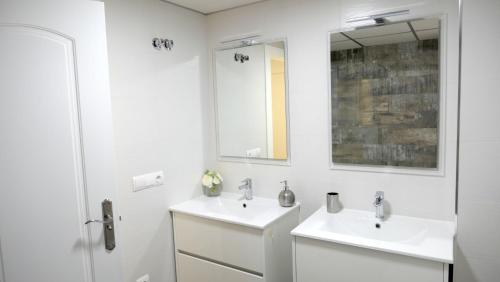 - une salle de bains blanche avec deux lavabos et un miroir dans l'établissement Slappe Jaén I, à Jaén