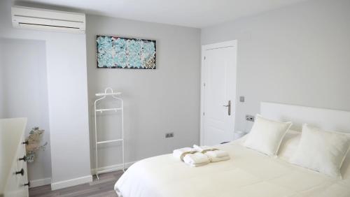 een witte slaapkamer met een wit bed en handdoeken erop bij Slappe Jaén I in Jaén