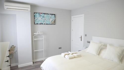a white bedroom with a white bed with towels on it at Slappe Jaén I in Jaén