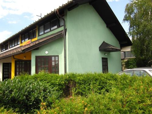 a green house with a car parked in front of it at Apartments Trzin-Mlake w FREE Parking in Trzin