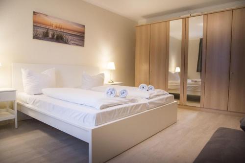 Un dormitorio con una gran cama blanca con toallas. en Am-Sahlenburger-Strand-1-Whg-15, en Cuxhaven