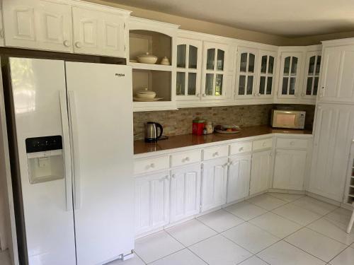 a white kitchen with white cabinets and a refrigerator at Spacious White House Villa 1 minute to sandy beaches in Saint James